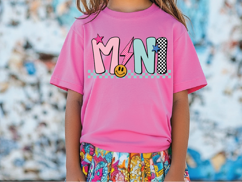 a little girl wearing a pink shirt with a smiley face