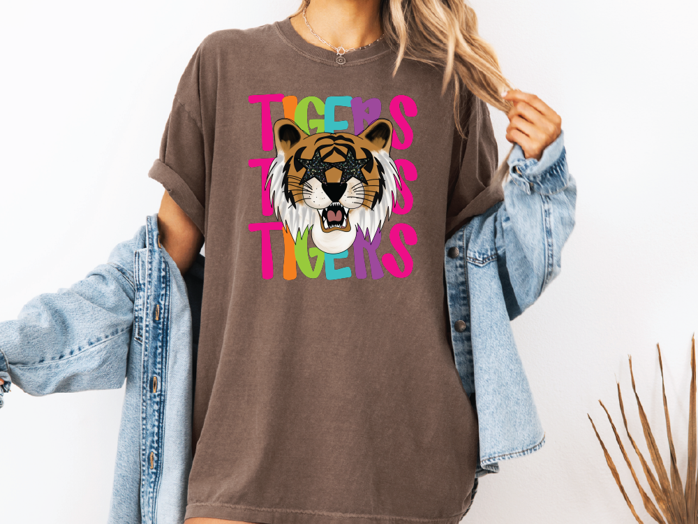 A woman wearing a brown t-shirt with a graphic of a tiger and the text "TIGERS" printed on it.