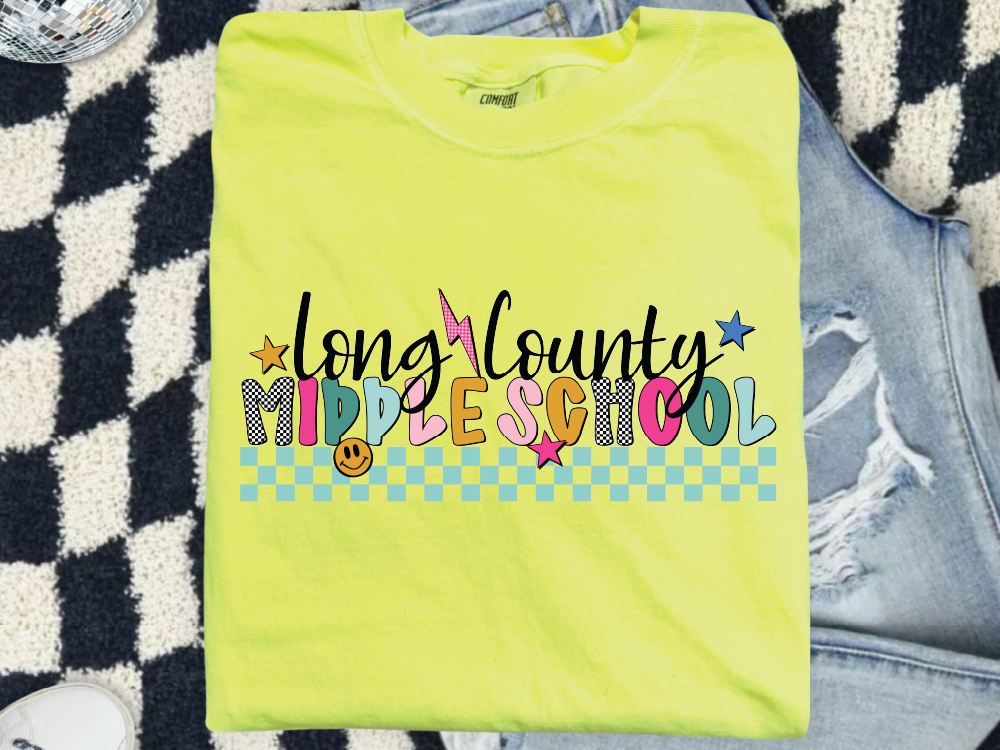 A bright yellow t-shirt with colorful text and graphics, including a smiley face, stars, and checkered patterns, is displayed on a patterned surface.