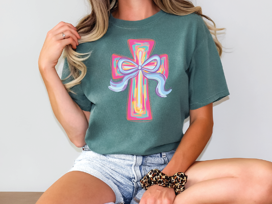 a woman sitting on a table wearing a green shirt with a cross on it