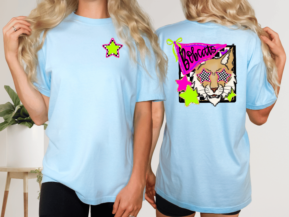 two women wearing light blue t-shirts with a graphic design featuring a cartoon-style tiger wearing sunglasses and a star.
