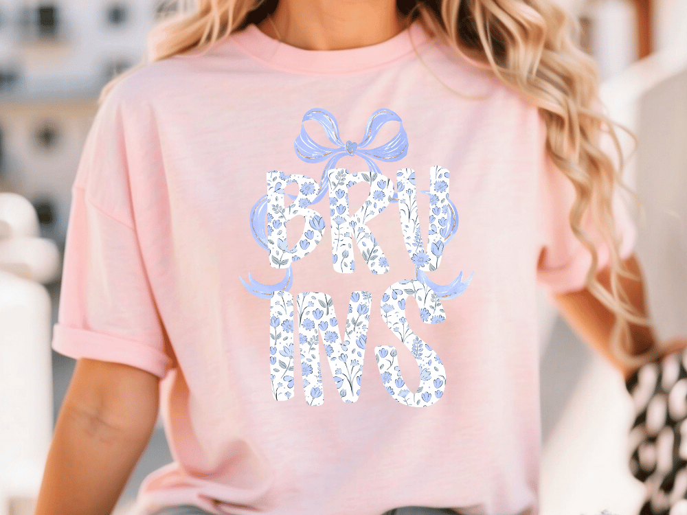 A woman wearing a pink t-shirt with the text "B.K.U.N.S." printed on it.