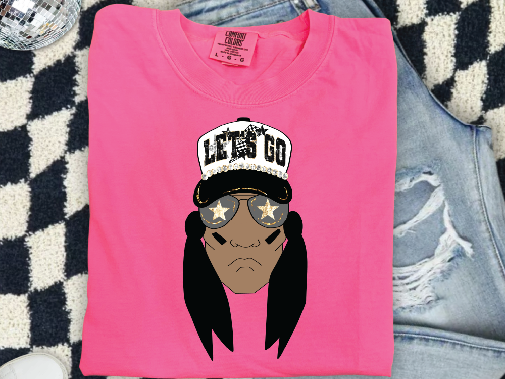 A pink t-shirt with a graphic design of a person wearing sunglasses and a hat with the text "LET'S GO" printed on it.