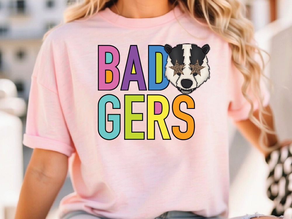 A woman wearing a pink t-shirt with the text "BAD GERS" printed on it.