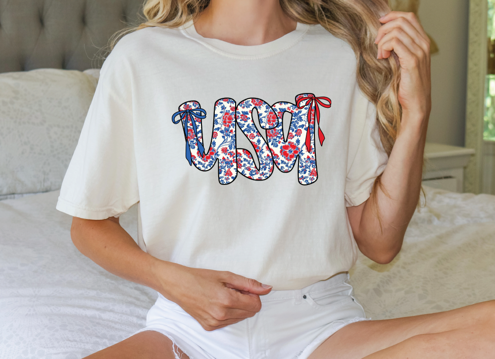 a woman sitting on a bed wearing a white shirt