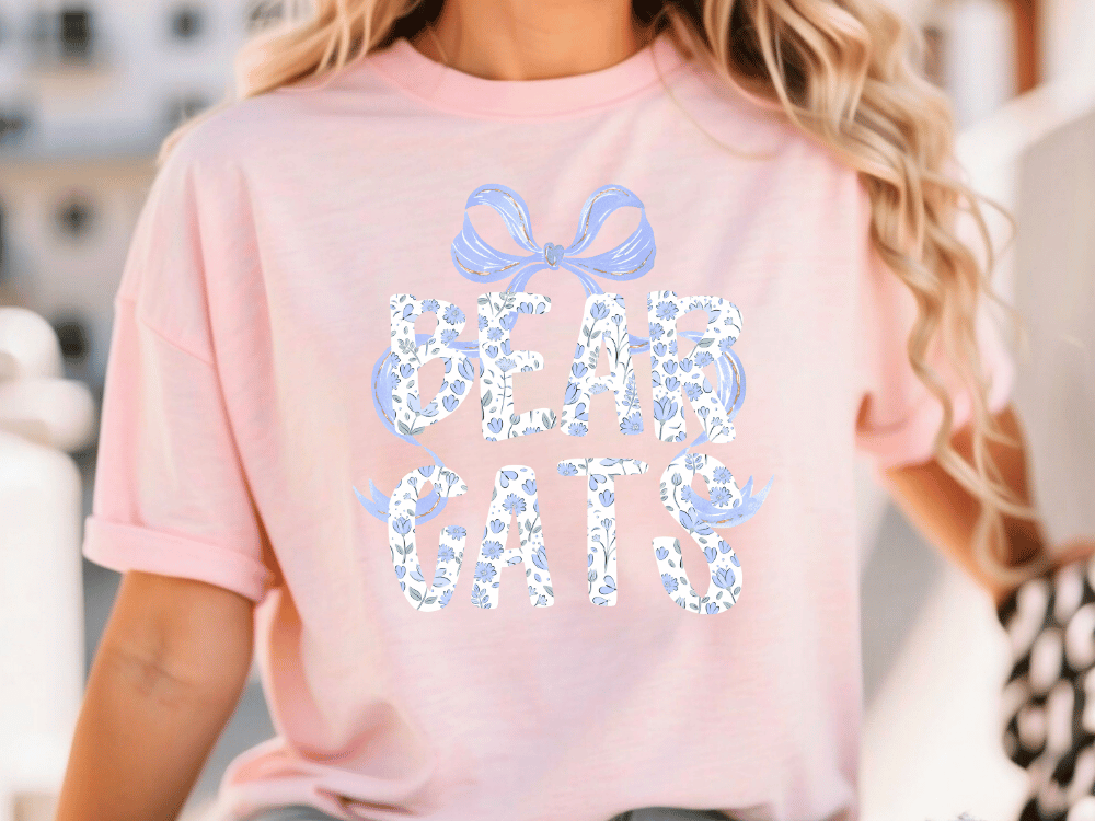A woman wearing a pink t-shirt with the text "BEAR GATTS" printed on it.
