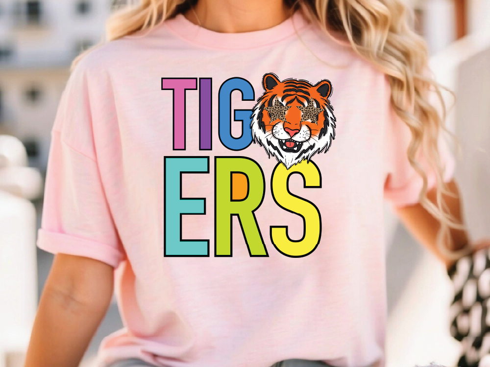 A woman wearing a pink t-shirt with the word "TIGERS" printed on it, featuring a tiger's face.