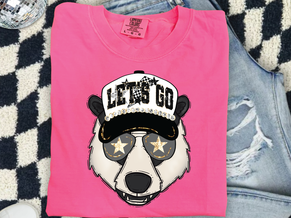 A pink t-shirt with a graphic of a panda wearing a hat with stars and the text "LET'S GO" printed on it.