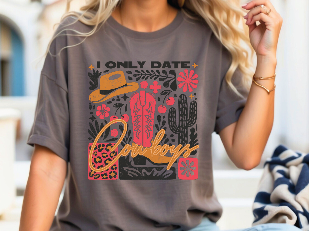 A woman wearing a grey t-shirt with a graphic design featuring various cowboy-related elements such as a cowboy hat, boots, and a cactus.