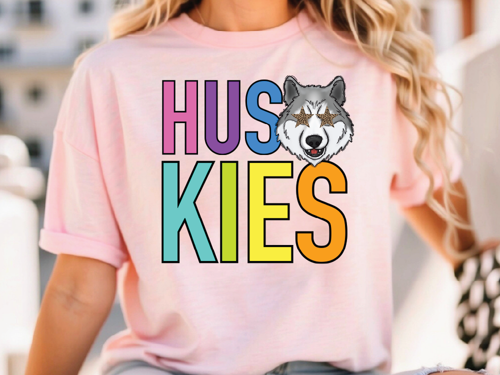 A person wearing a pink t-shirt with the text "HUSKIES" and a graphic of a wolf's head.