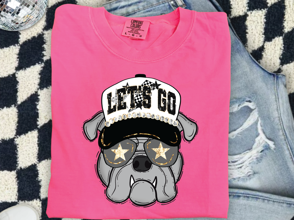 A pink t-shirt with a graphic of a dog wearing sunglasses and a hat with the text "LET'S GO" printed on it.