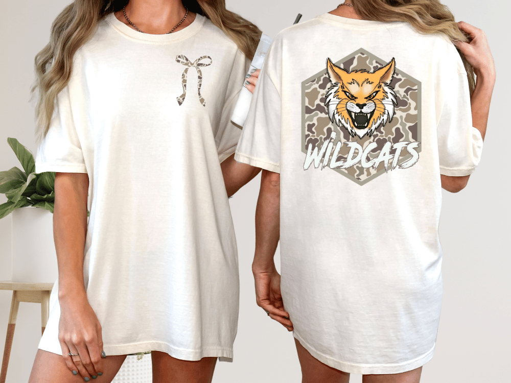 two different views of a white t-shirt with a graphic design on the back. The design features a cartoon-like wildcat with a bow on its neck and the word "WILDCATS" written below it.