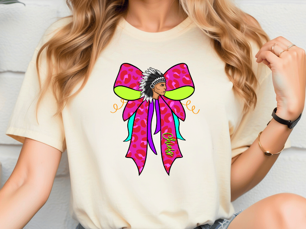 A woman wearing a white t-shirt with a colorful graphic design featuring a stylized female figure with a large pink bow on her head.