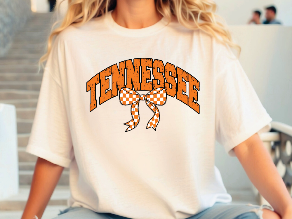 A person wearing a white t-shirt with the word "TENNESSEE" and a checkered bow printed on it.