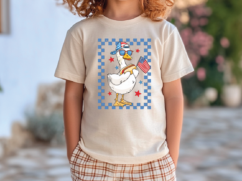 a little girl wearing a t - shirt with a duck on it