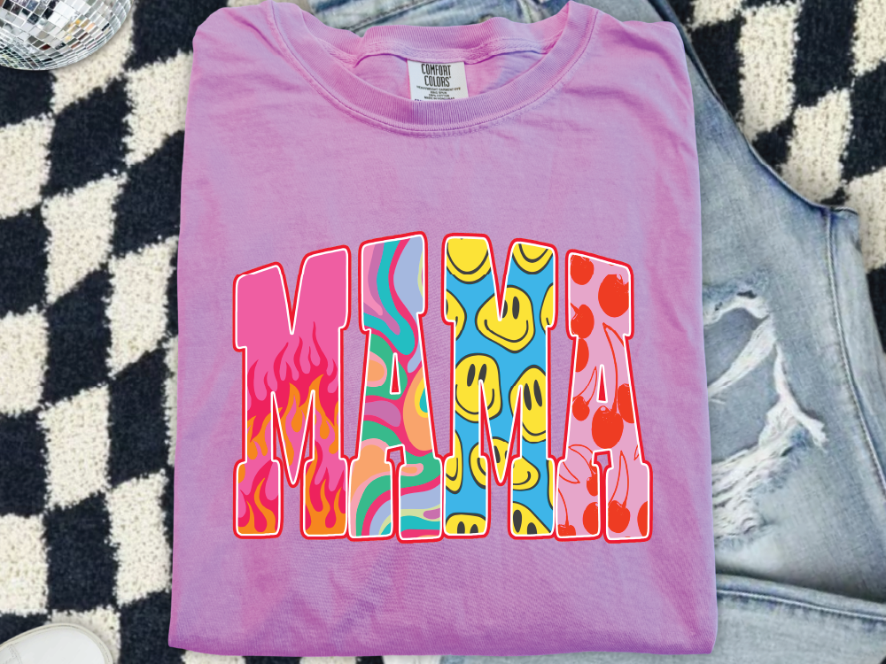 A pink t-shirt with a colorful graphic design featuring the word "MAMA" in a stylized font.