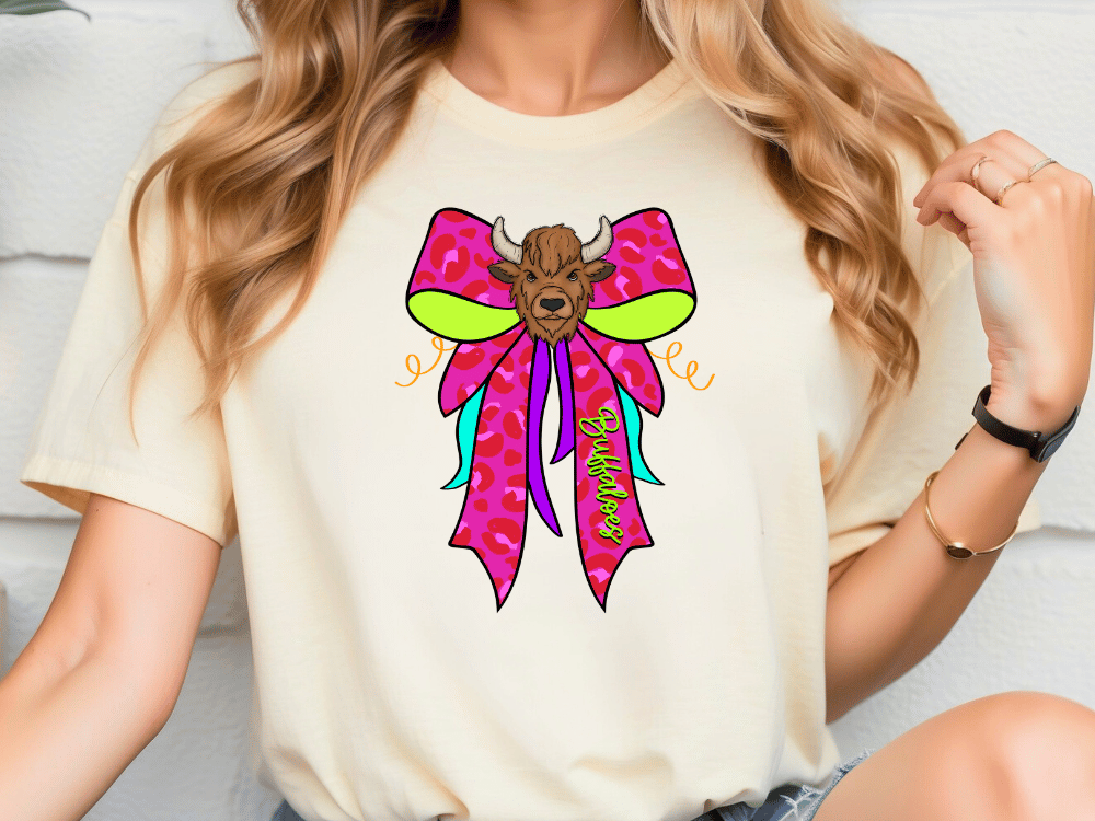 A woman wearing a white t-shirt with a colorful graphic design of a bull's head on a bow.