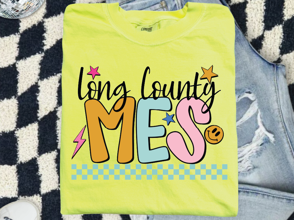 A yellow t-shirt with colorful text and graphics printed on it, placed on a checkered surface.