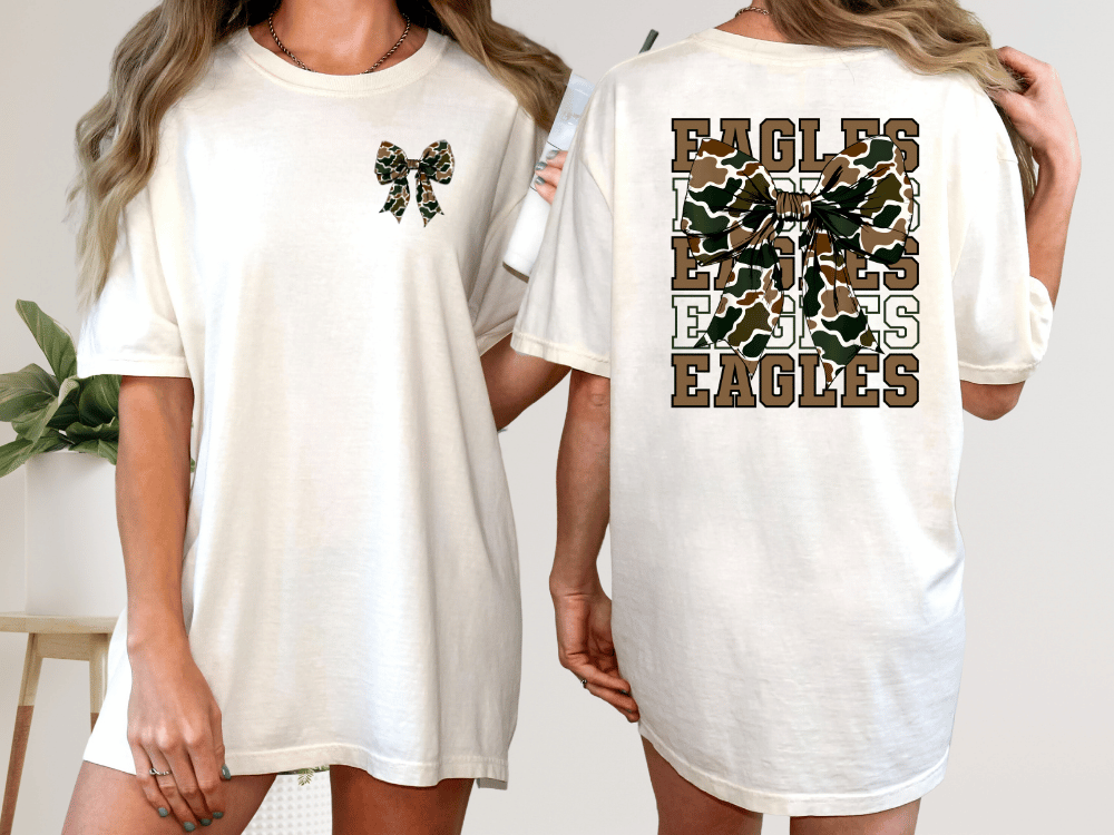 A woman wearing a white t-shirt with a large bow on the front and the word "EAGLES" printed on the back.