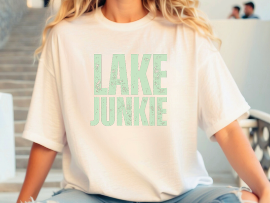 a woman sitting on the ground wearing a lake junkie t - shirt