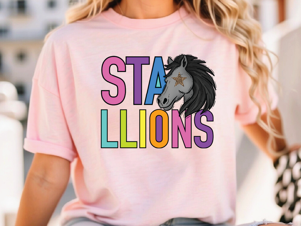 A woman wearing a pink t-shirt with a graphic design of a horse's head and the text "STALLIONS" printed on it.