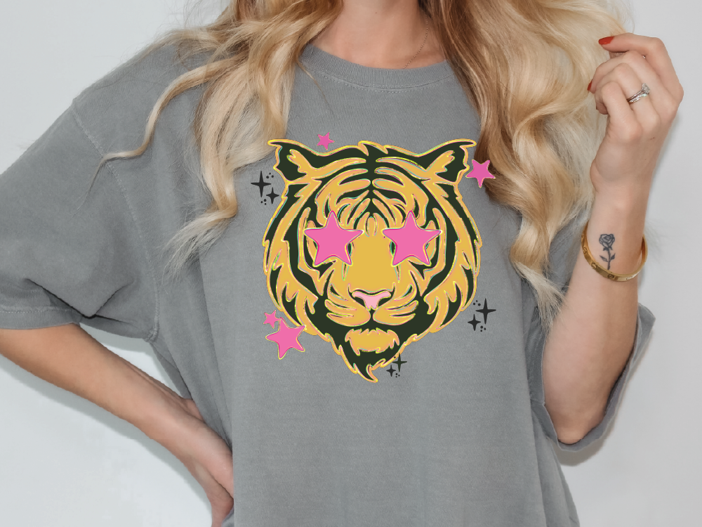 A woman wearing a gray t-shirt with a graphic design of a tiger's face and pink stars.