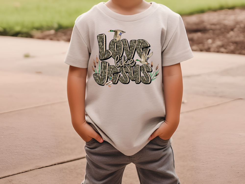 A child wearing a white t-shirt with the text "Love is like Jesus" printed on it.