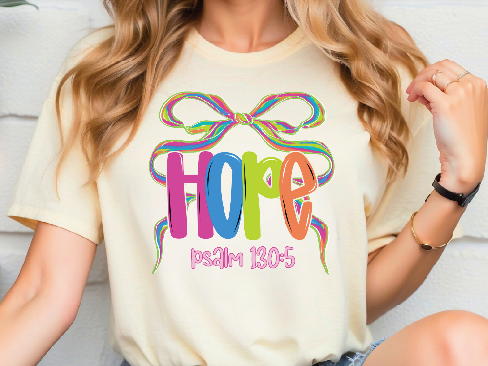 A woman wearing a white t-shirt with a colorful graphic design featuring the word "HOPE" and a ribbon.