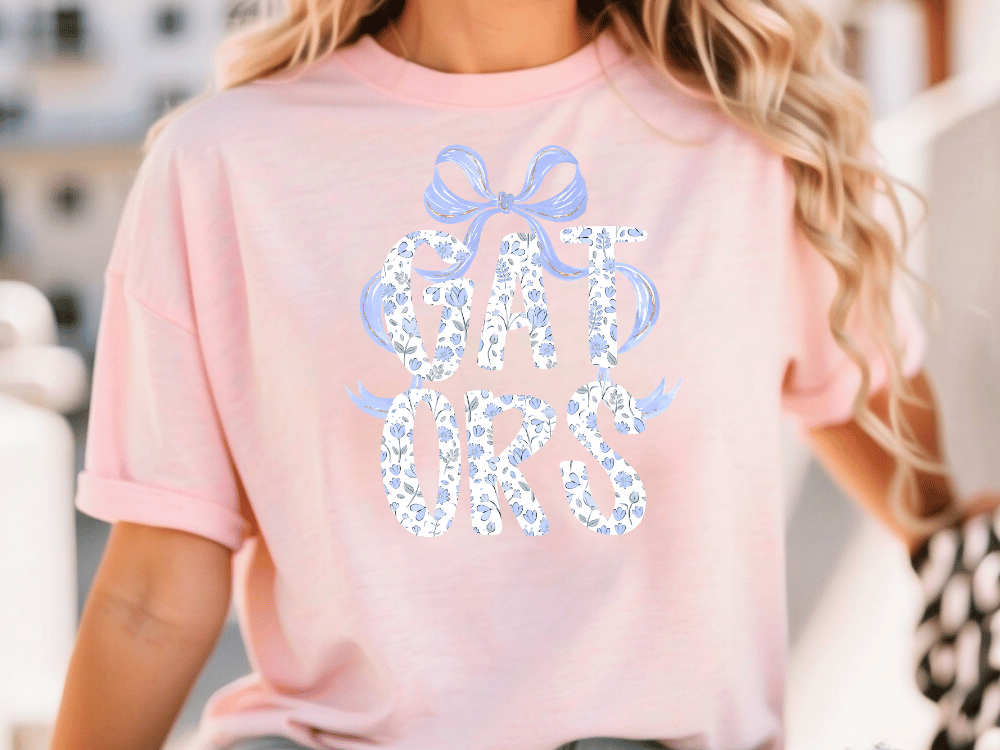 A woman wearing a pink t-shirt with the text "GATORS" printed on it.