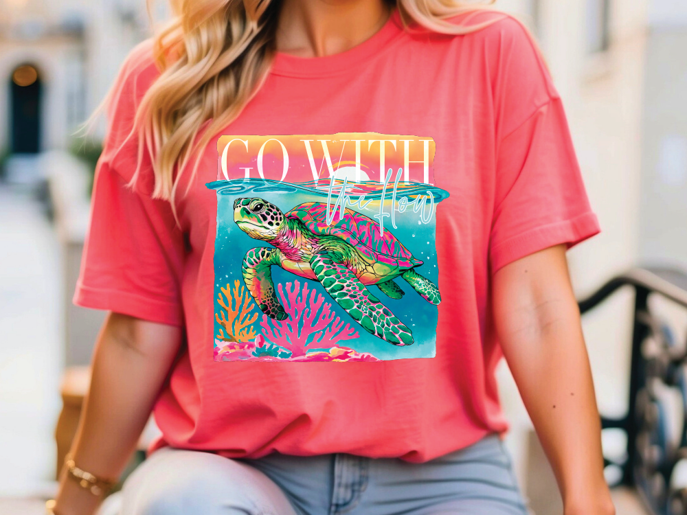 A woman wearing a red t-shirt with a colorful graphic of a turtle swimming in the ocean.