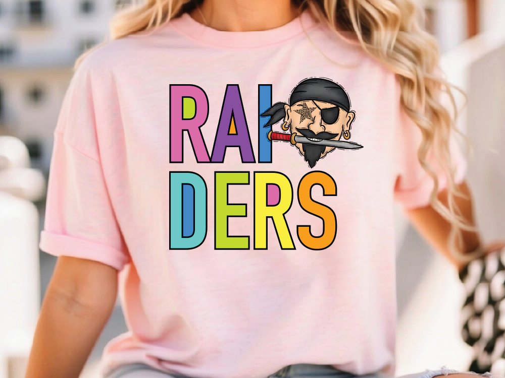 A person wearing a pink t-shirt with the text "RAI DERS" printed on it, along with a cartoon pirate character.