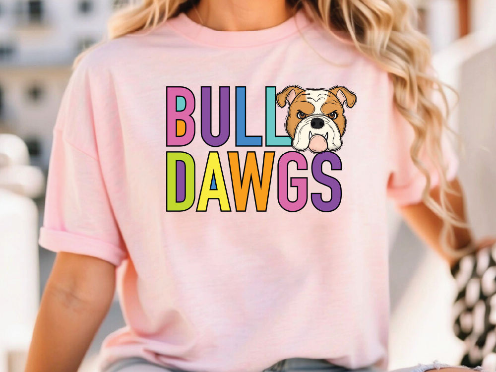 A woman wearing a pink t-shirt with the text "BULL DAWGS" printed on it, along with a cartoon image of a bulldog.