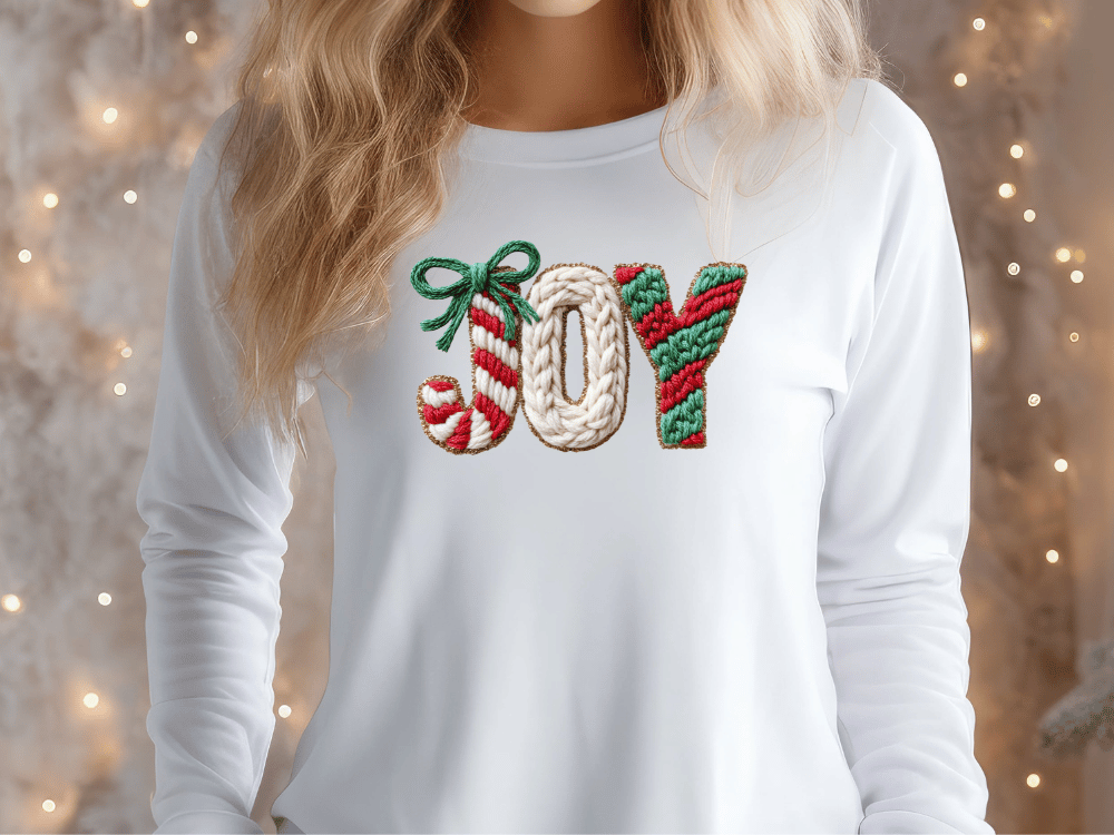 A woman wearing a white long-sleeved shirt with the word "Joy" embroidered on it.
