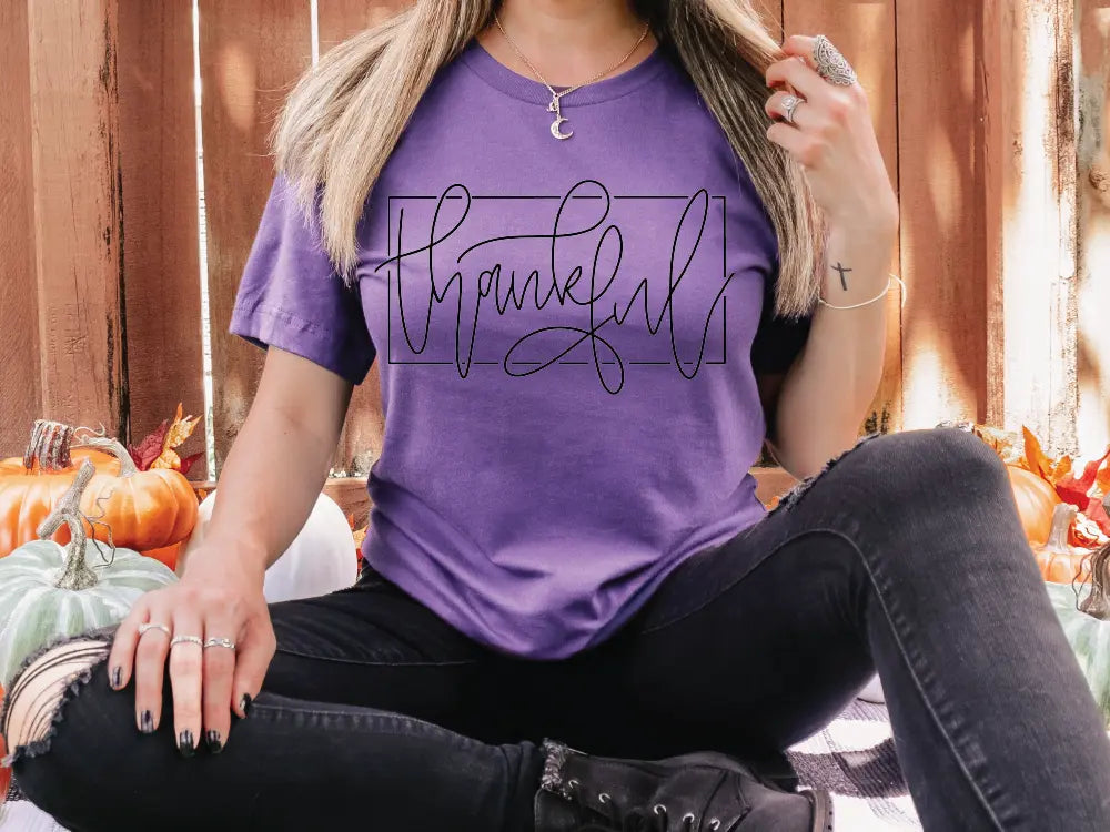 a woman sitting on the ground wearing a purple shirt