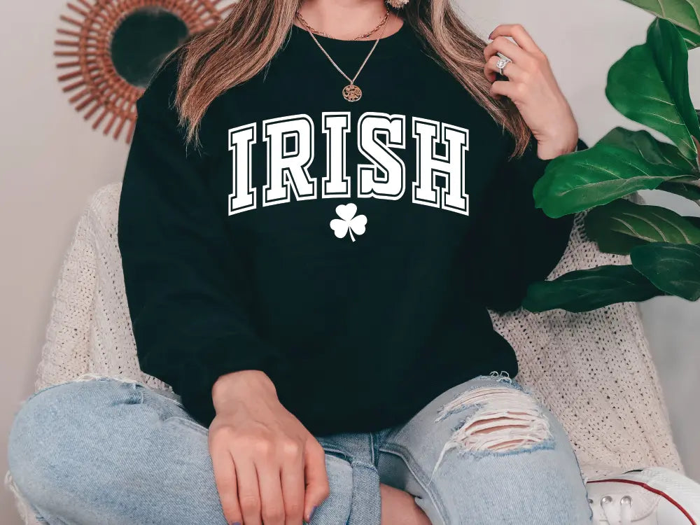 a woman sitting on a couch wearing a black irish sweatshirt