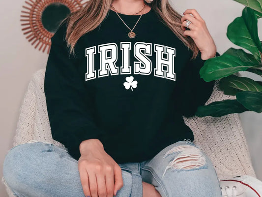 a woman sitting on a couch wearing a black irish sweatshirt