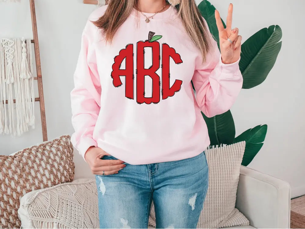 a woman wearing a pink sweatshirt with an apple on it