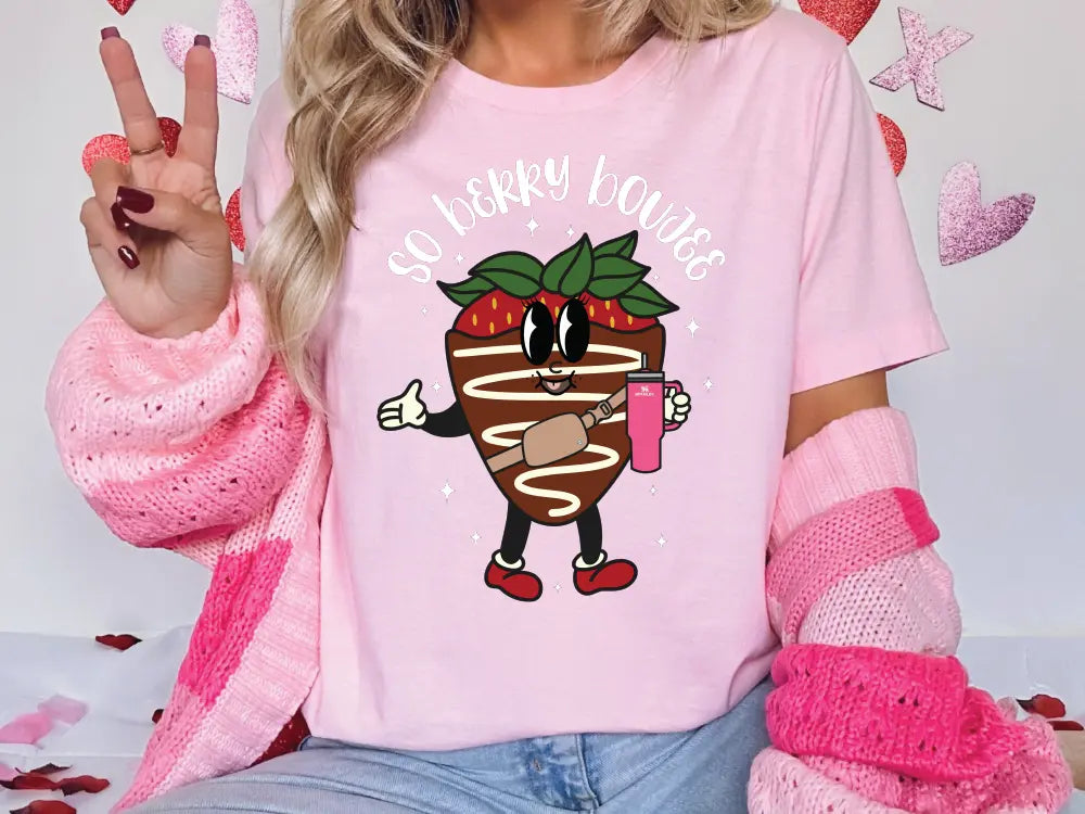 a woman wearing a pink shirt with a strawberry on it