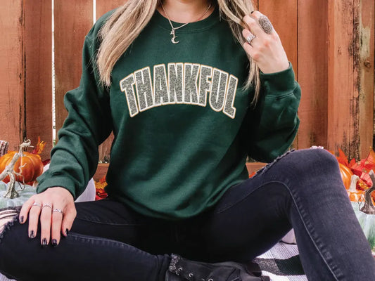 a woman sitting on the ground wearing a green sweatshirt