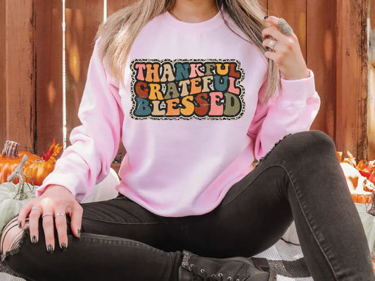 a woman sitting on the ground wearing a pink sweatshirt