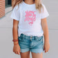 a little girl wearing a white shirt and blue shorts