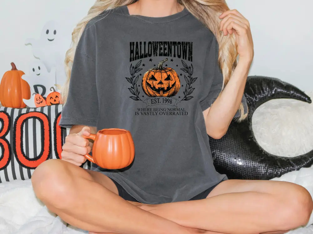 a woman sitting on a bed holding a pumpkin mug