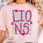 A woman wearing a pink t-shirt with a graphic design featuring the word "LIONS" in pink and black polka dots.