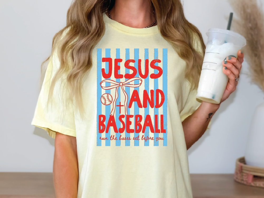 A woman wearing a yellow t-shirt with a graphic design that says "JESUS AND BASEBALL run the bases not before you".