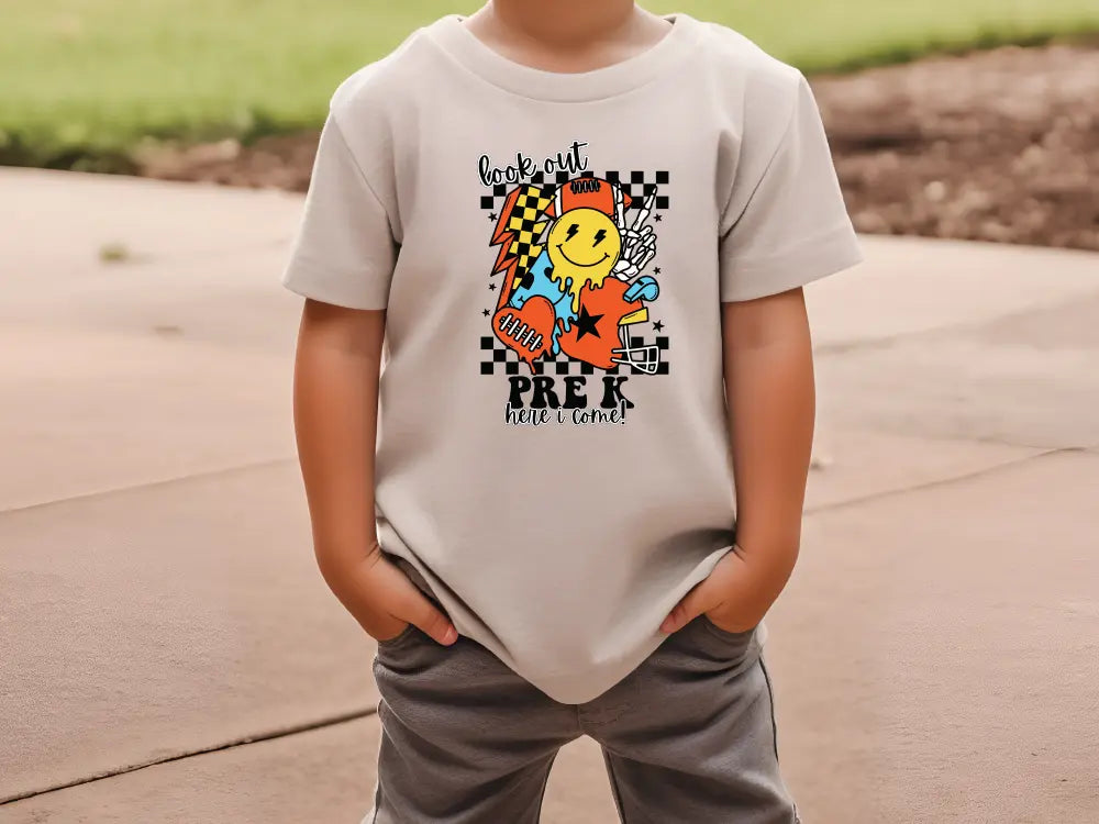 a young boy standing on a sidewalk wearing a t - shirt