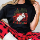 a woman sitting on a couch wearing a christmas t - shirt