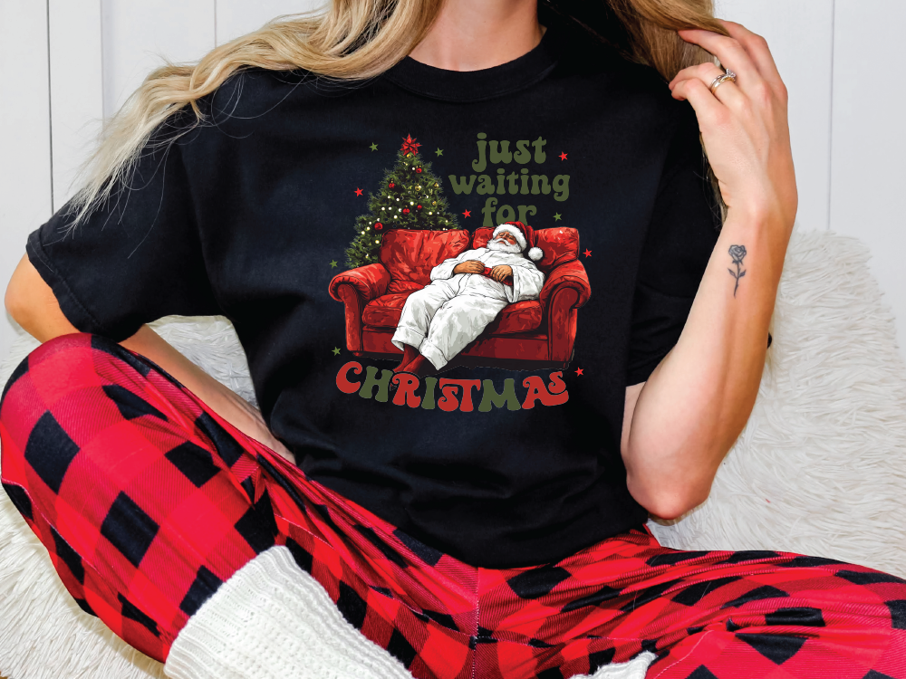 a woman sitting on a couch wearing a christmas t - shirt