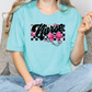 a woman sitting on a couch wearing a turquoise shirt with a pink bow