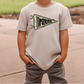 A child wearing a white t-shirt with a dragon design and gray pants standing on a concrete surface.