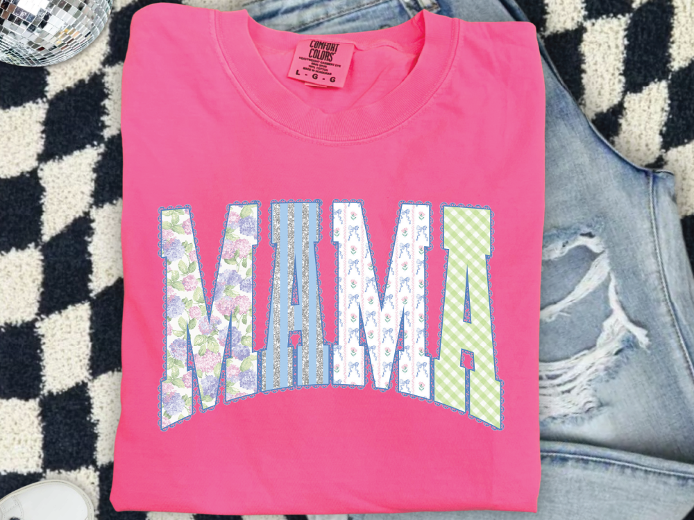A pink t-shirt with the word "MAMA" printed on it, along with a denim jacket and a checkered blanket.